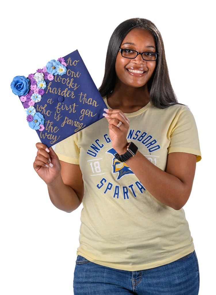 Asya Settle with her decorated graduation cap. It reads "No one works harder than a first gen who is paving the way"