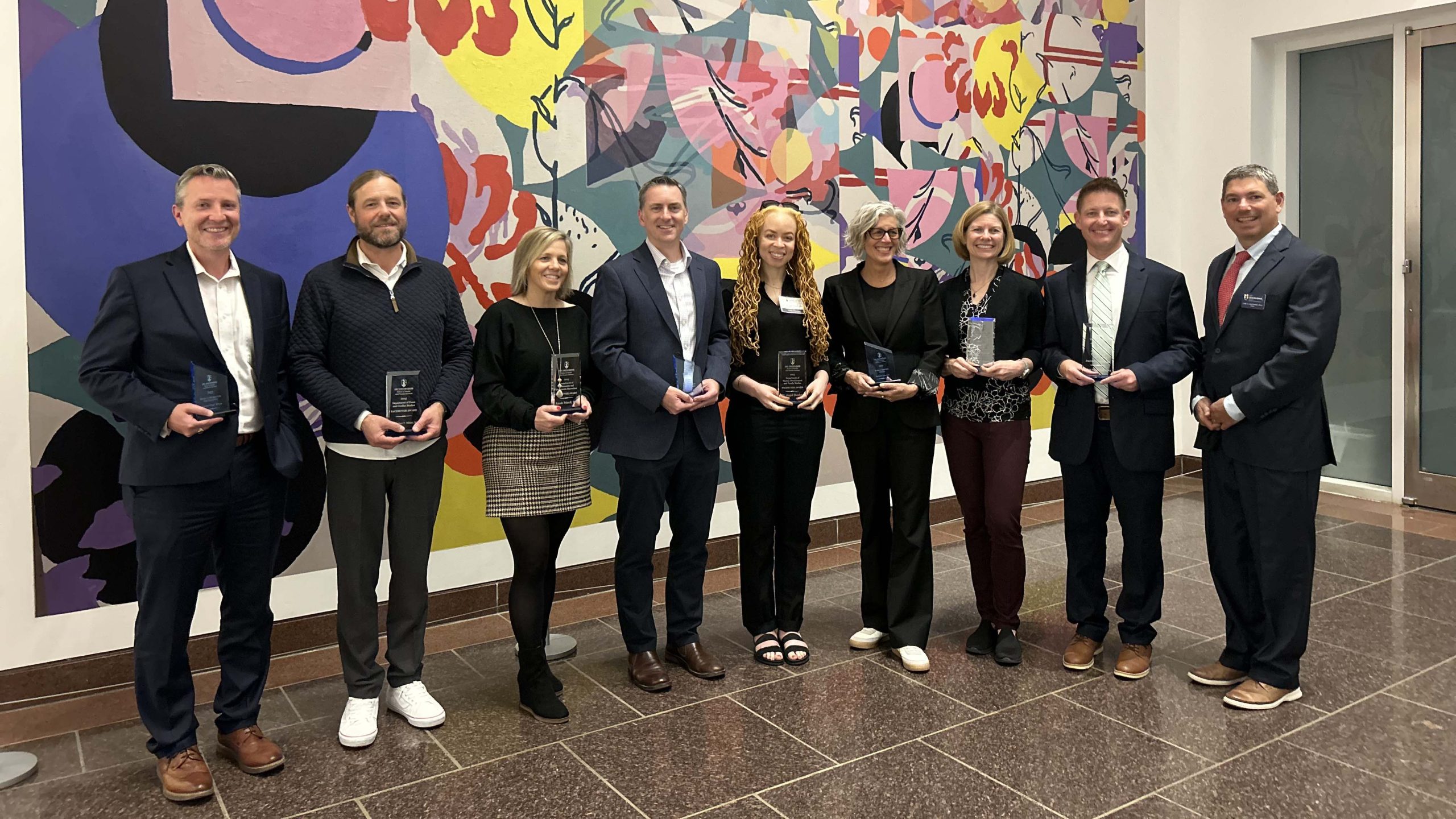 Alumni awardees holding their awards, in from of the artwork:Sheena Rose's: Pause and Breathe, We Got This